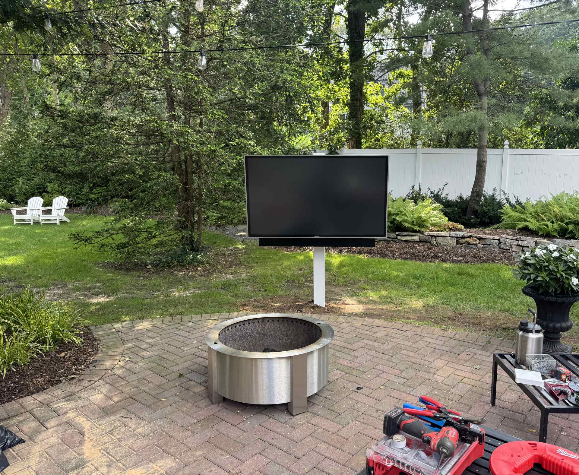 Finished outdoor TV mounted near a stainless steel fire pit on a Northport, NY patio