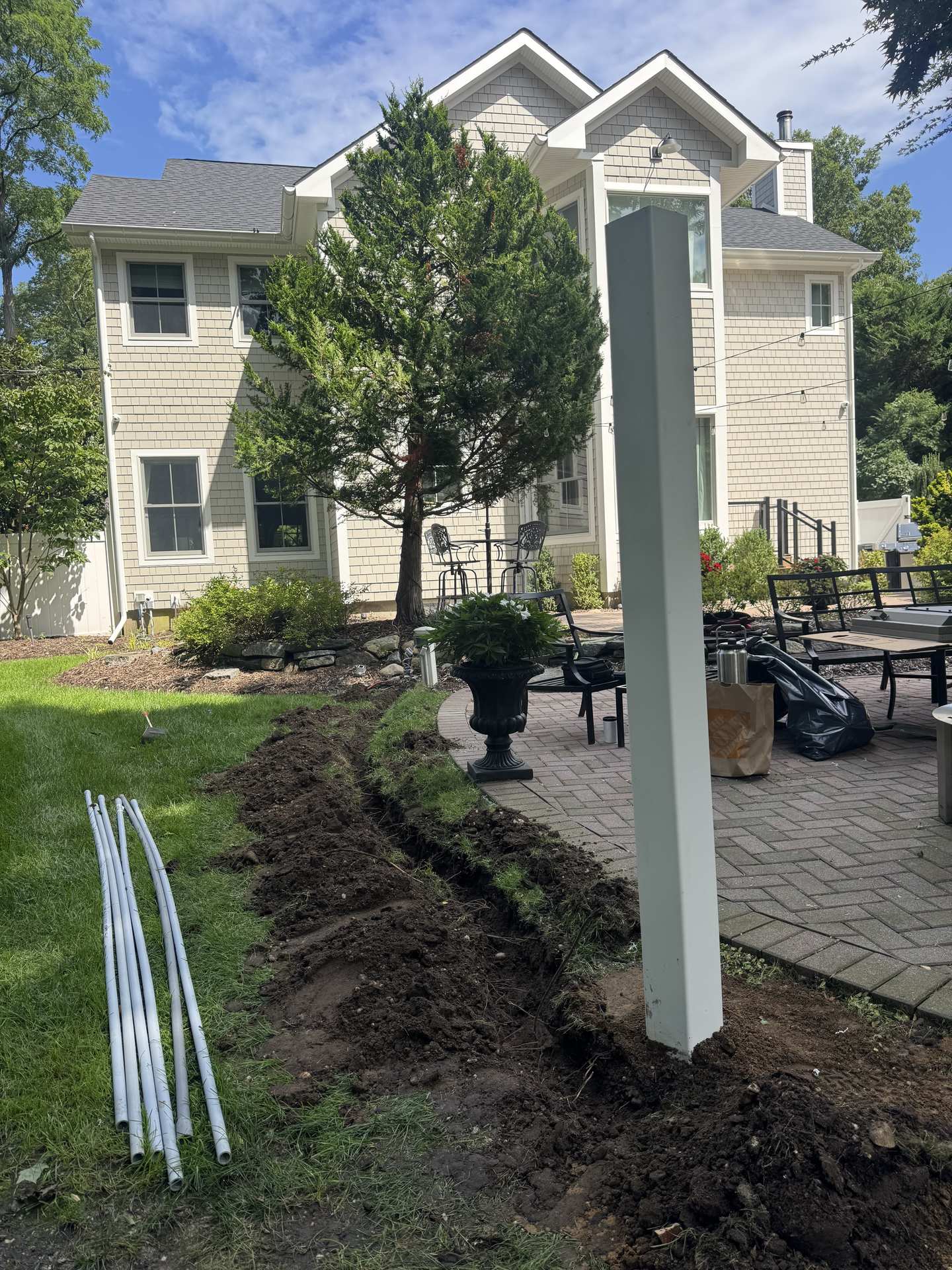 Trenching and conduit run across a Northport, NY backyard for an outdoor TV installation